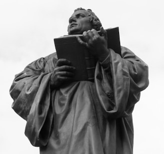 grayscale photo of woman holding book statue
