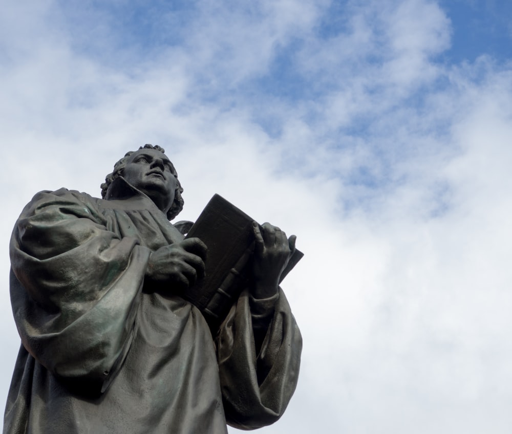 Estatua del hombre en el abrigo bajo el cielo azul durante el día