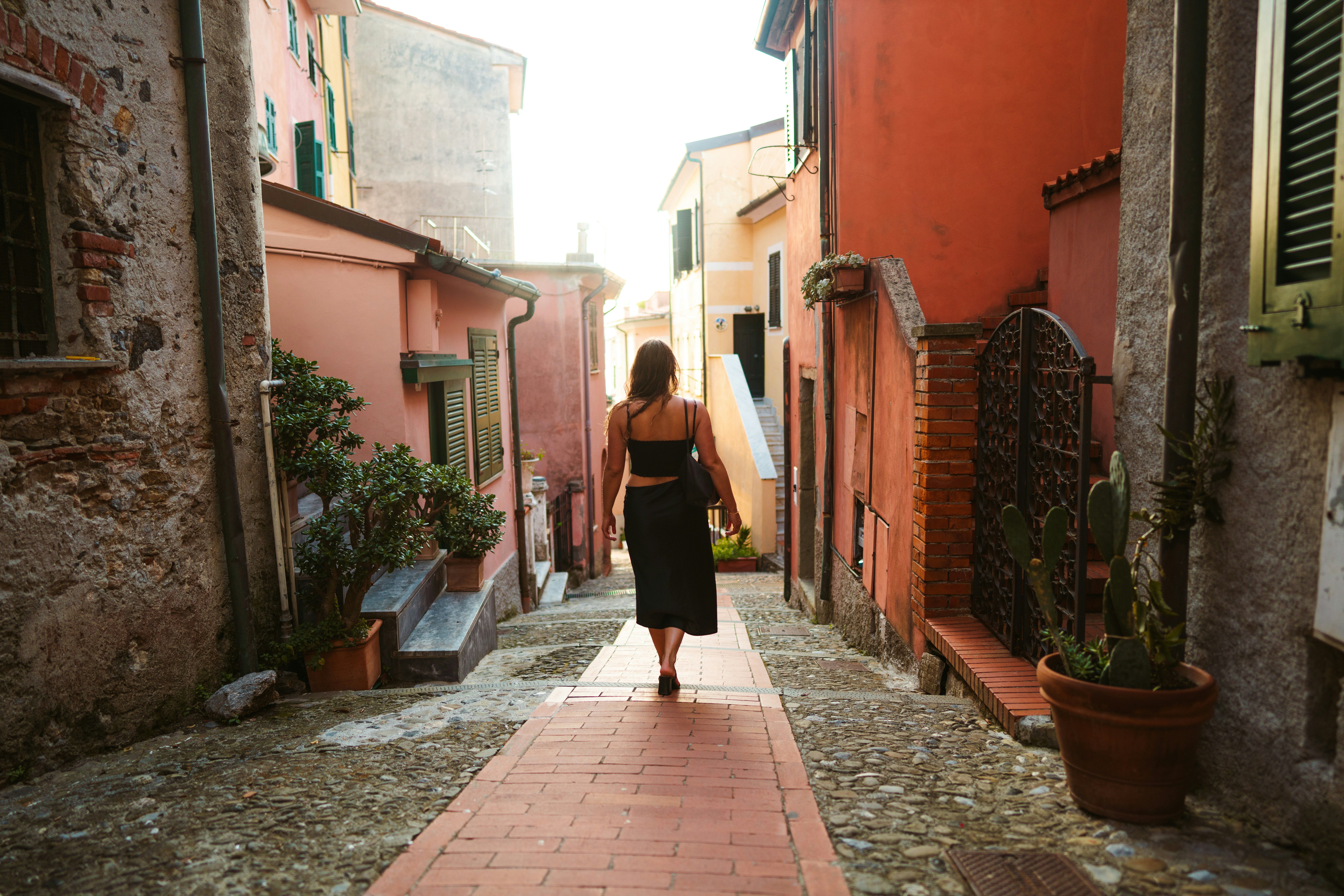 Femme en robe noire marchant sur le trottoir pendant la journée photo