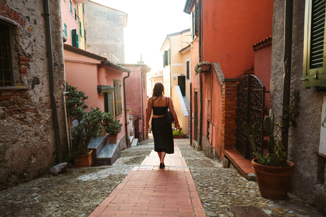 woman in black dress walking on sidewalk during daytime