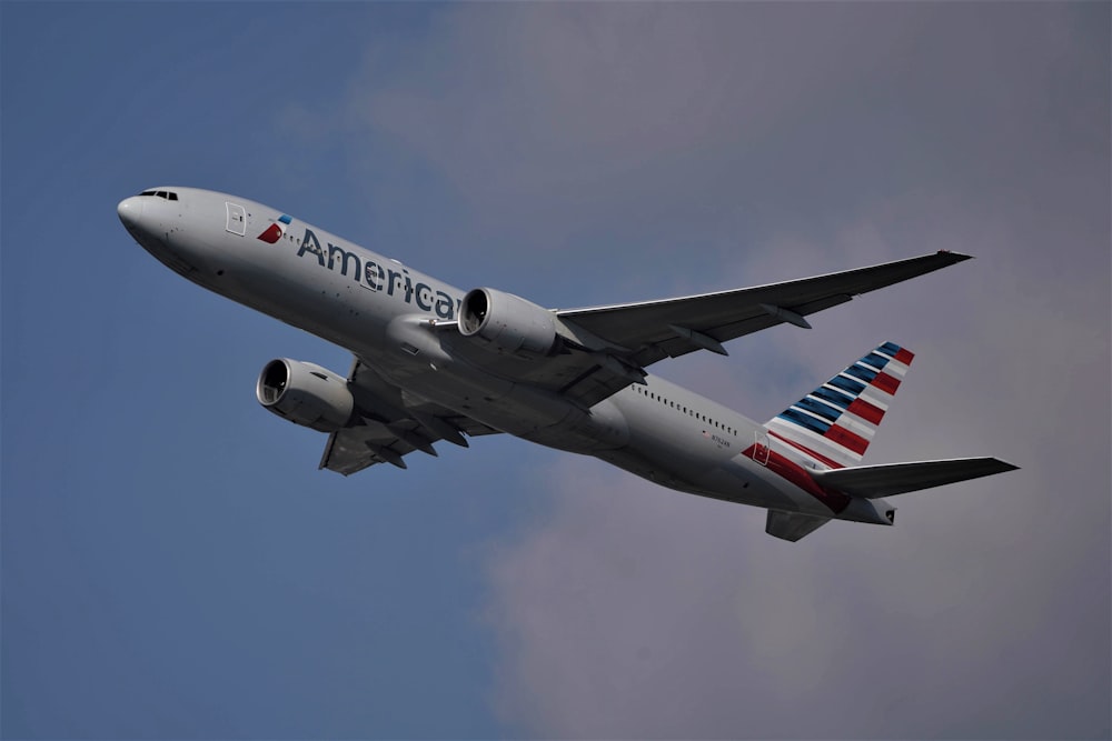 white and red passenger plane flying in the sky during daytime