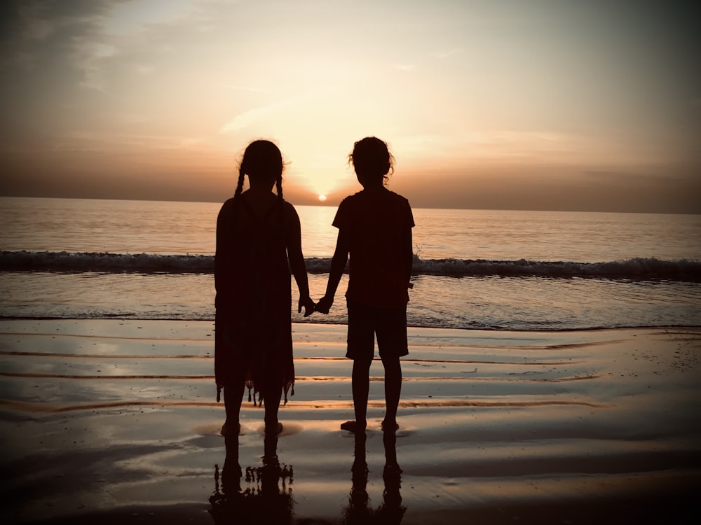 silhouette of couple standing on beach during sunset