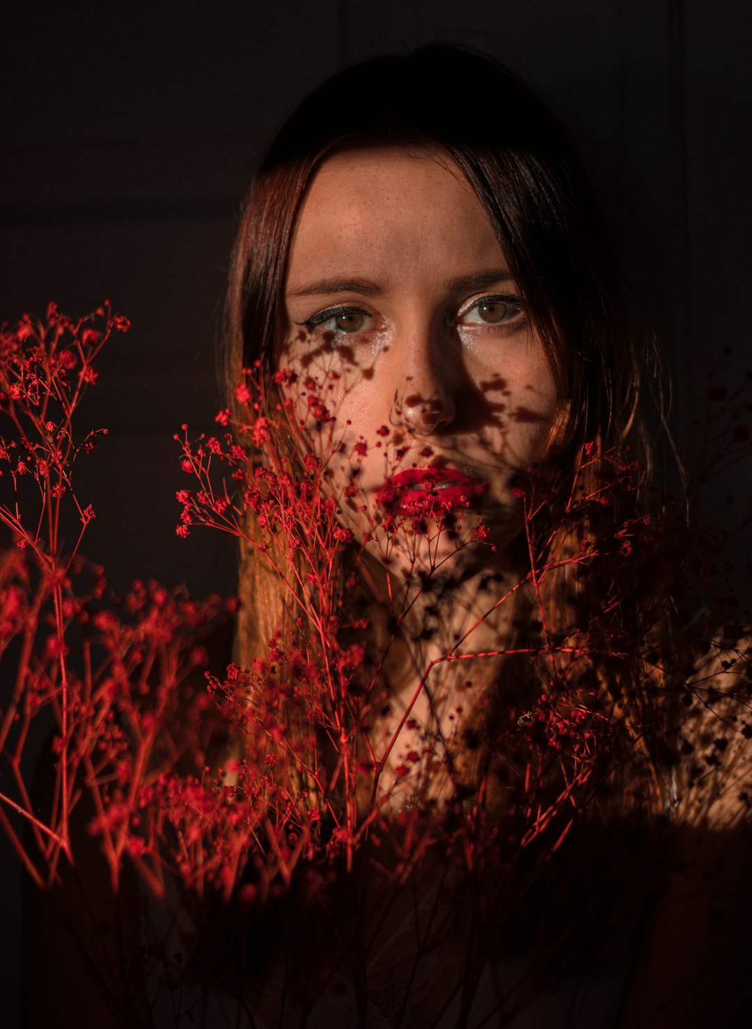 woman with red flower petals on her face