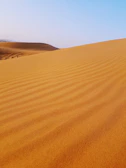 A serene desert landscape with golden dunes under a clear blue sky, inviting adventure.