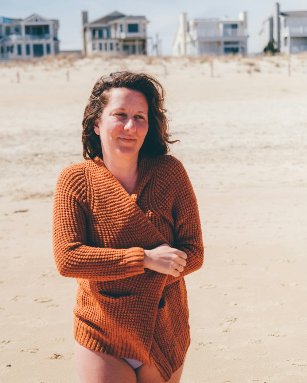 woman in red knit sweater standing on beach during daytime