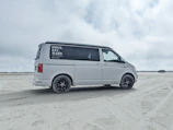 Delivery van parked near a beach house with rental gear being unloaded.
