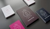 Several stacks of cards are laid out on a dark surface, each featuring different cover designs and labels. The cards include icons such as a cupcake with a candle, a heart, a condom, and a lightning cloud. The titles on the cards include 'Level 1,' 'Kamasutra,' and 'Gamechanger.' The cards have backgrounds in different colors such as white, black, and pink.