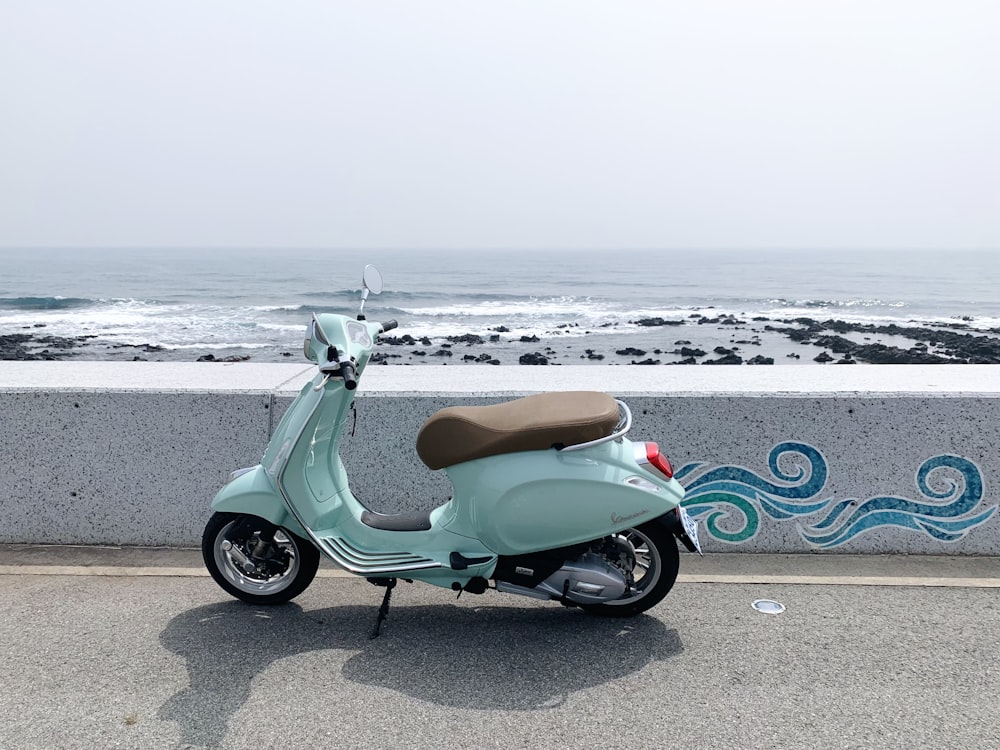 scooter motor verde estacionado na costa da praia durante o dia