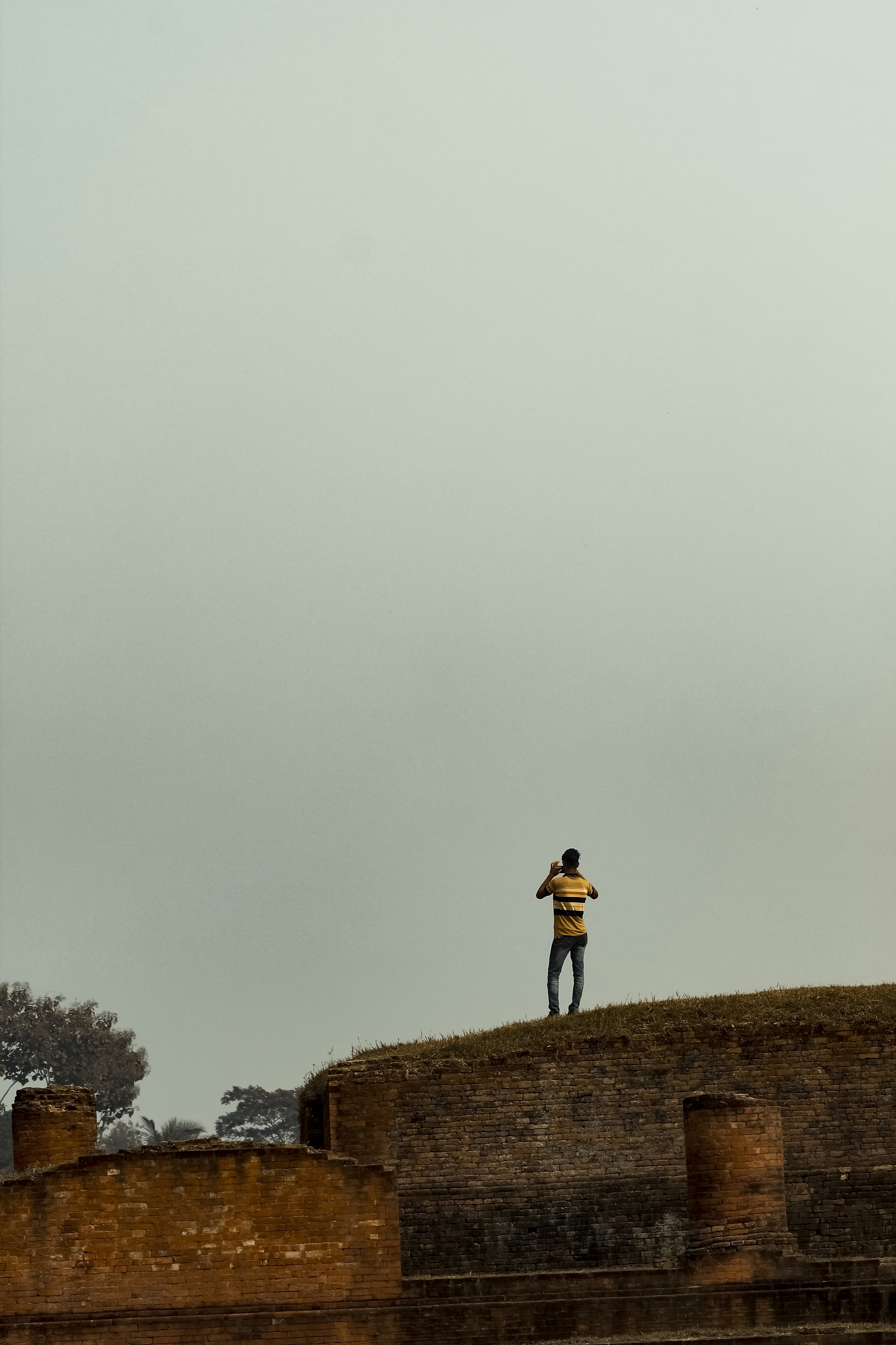 Hombre con chaqueta negra y jeans de mezclilla azul de pie en un campo de hierba marrón durante el día