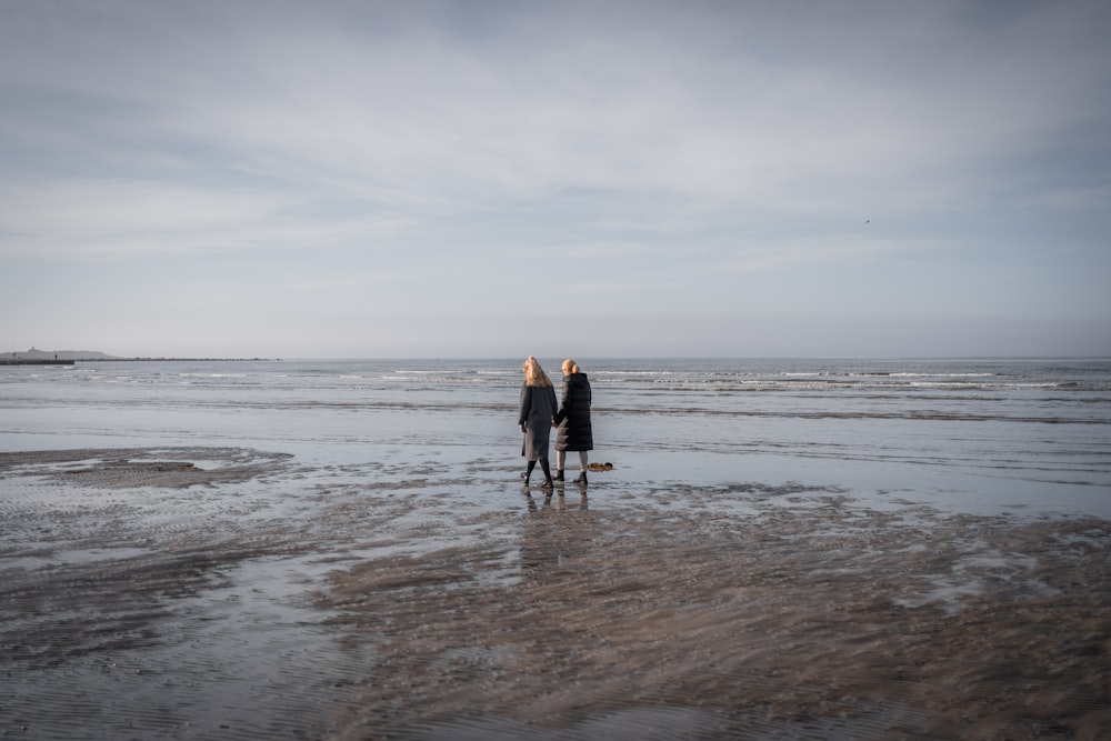 man and woman walking on beach during daytime