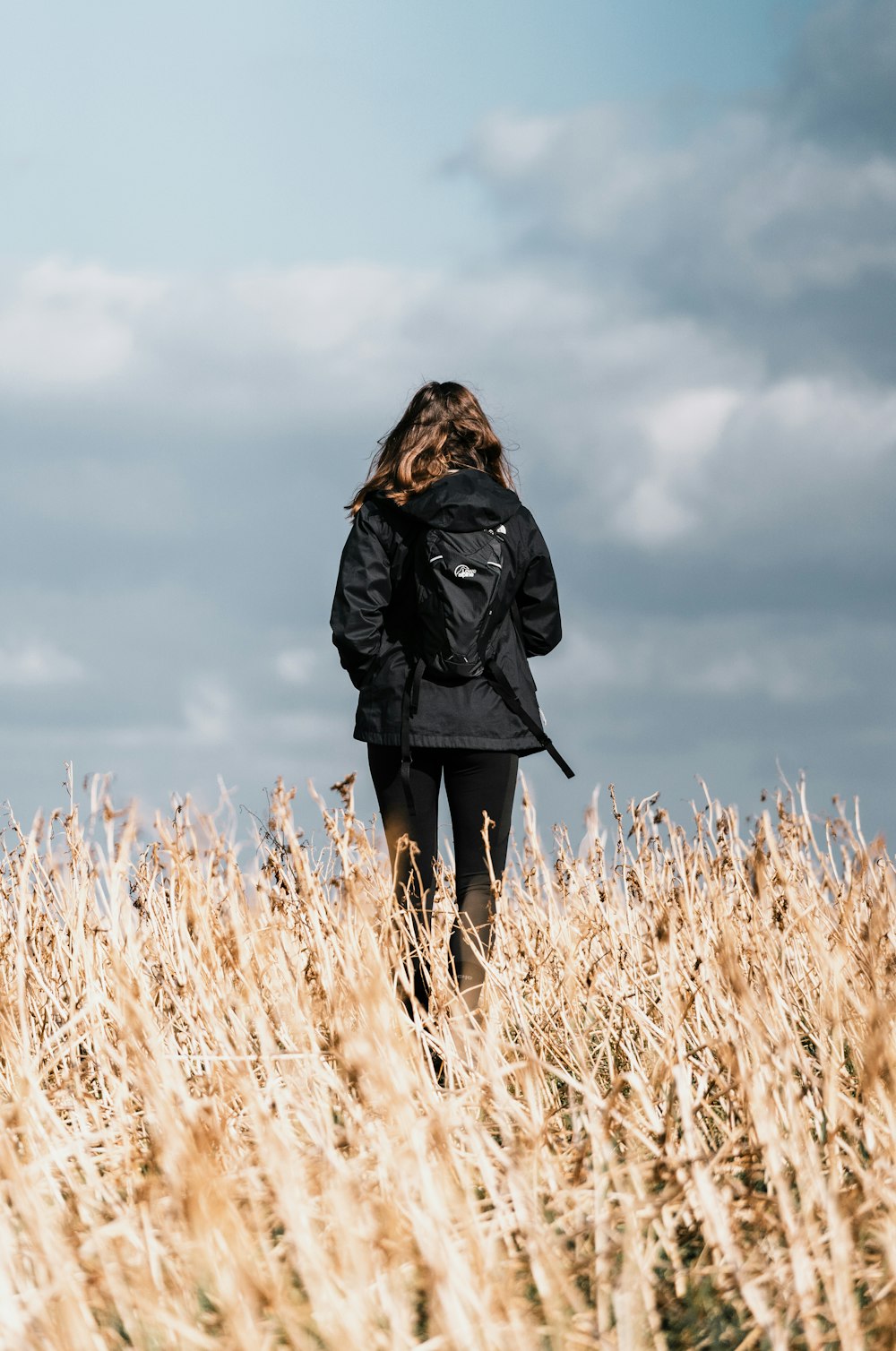 woman in black coat standing on brown grass field during daytime