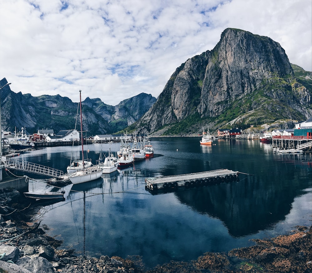 white and black boat on body of water near mountain during daytime