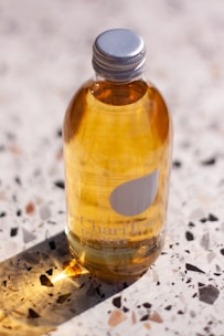 Minimalist clear bottle with a golden cap, highlighted by soft natural light on a velvet cloth.