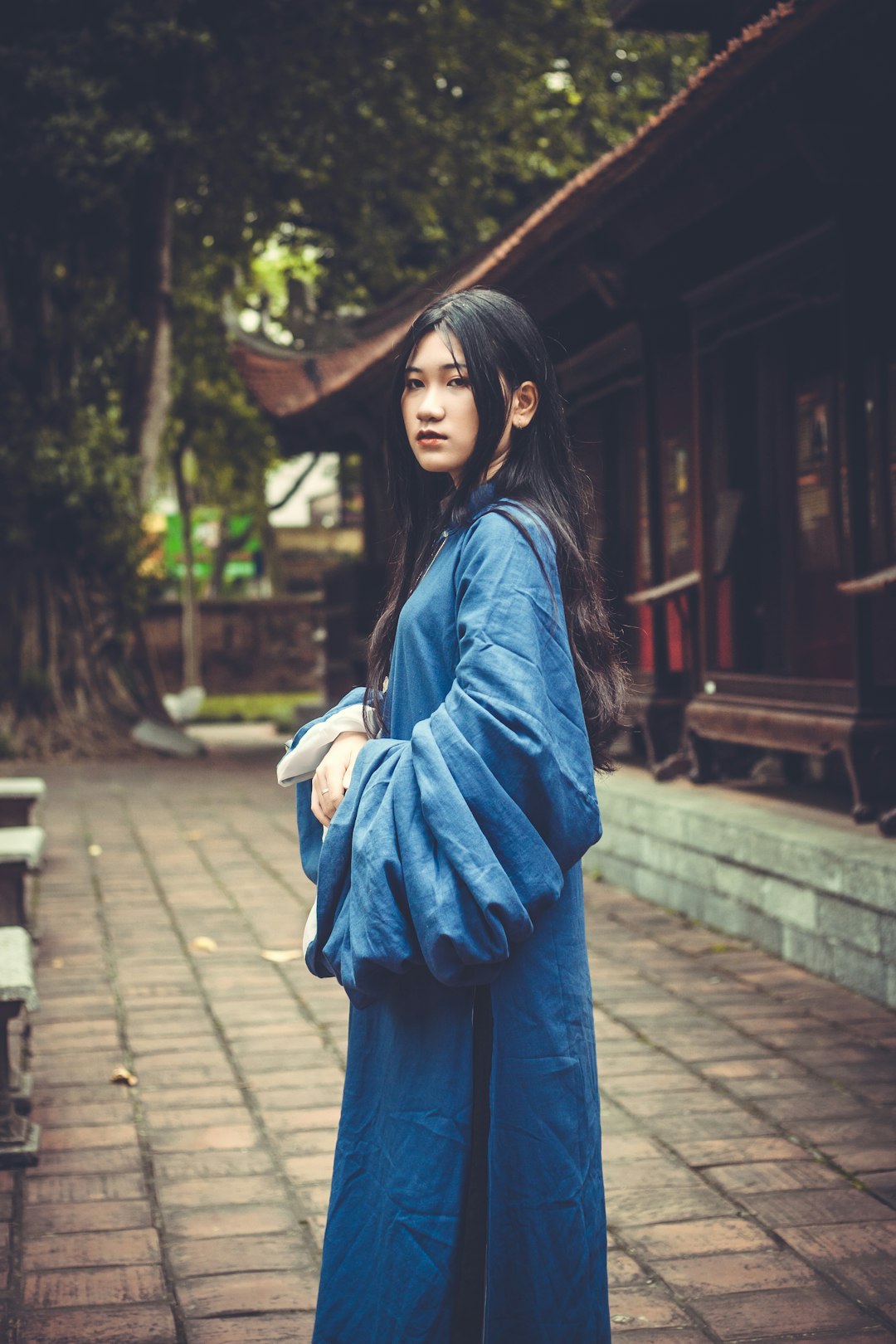 woman in blue long sleeve dress standing on sidewalk during daytime