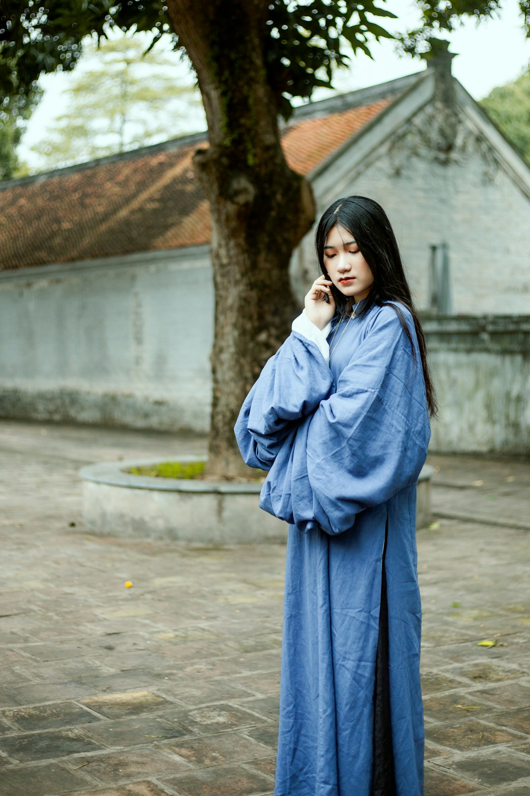 woman in blue long sleeve dress standing on sidewalk during daytime