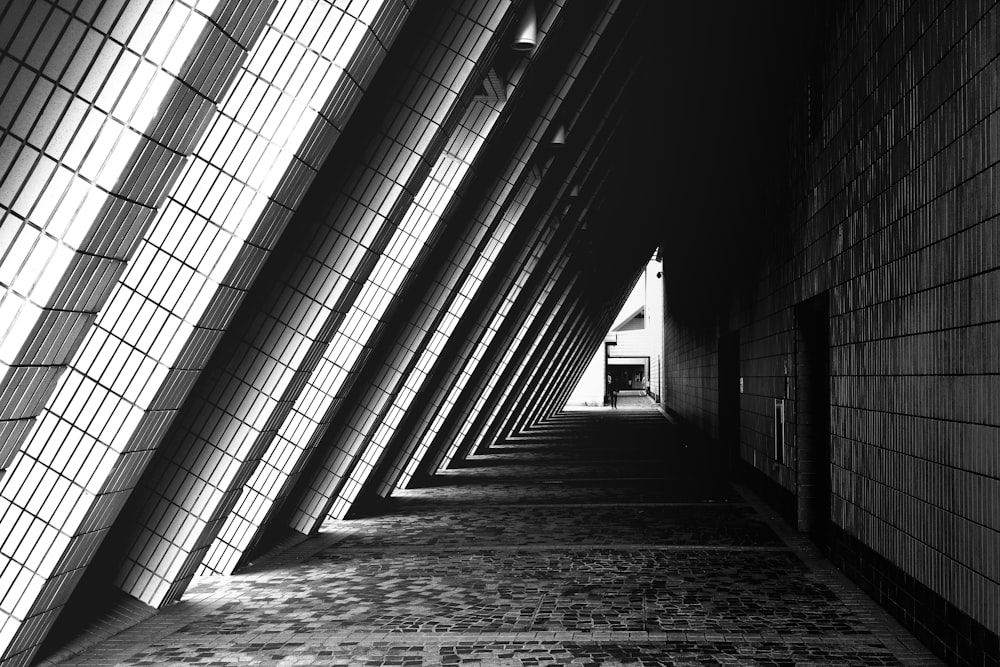 grayscale photo of person walking on hallway