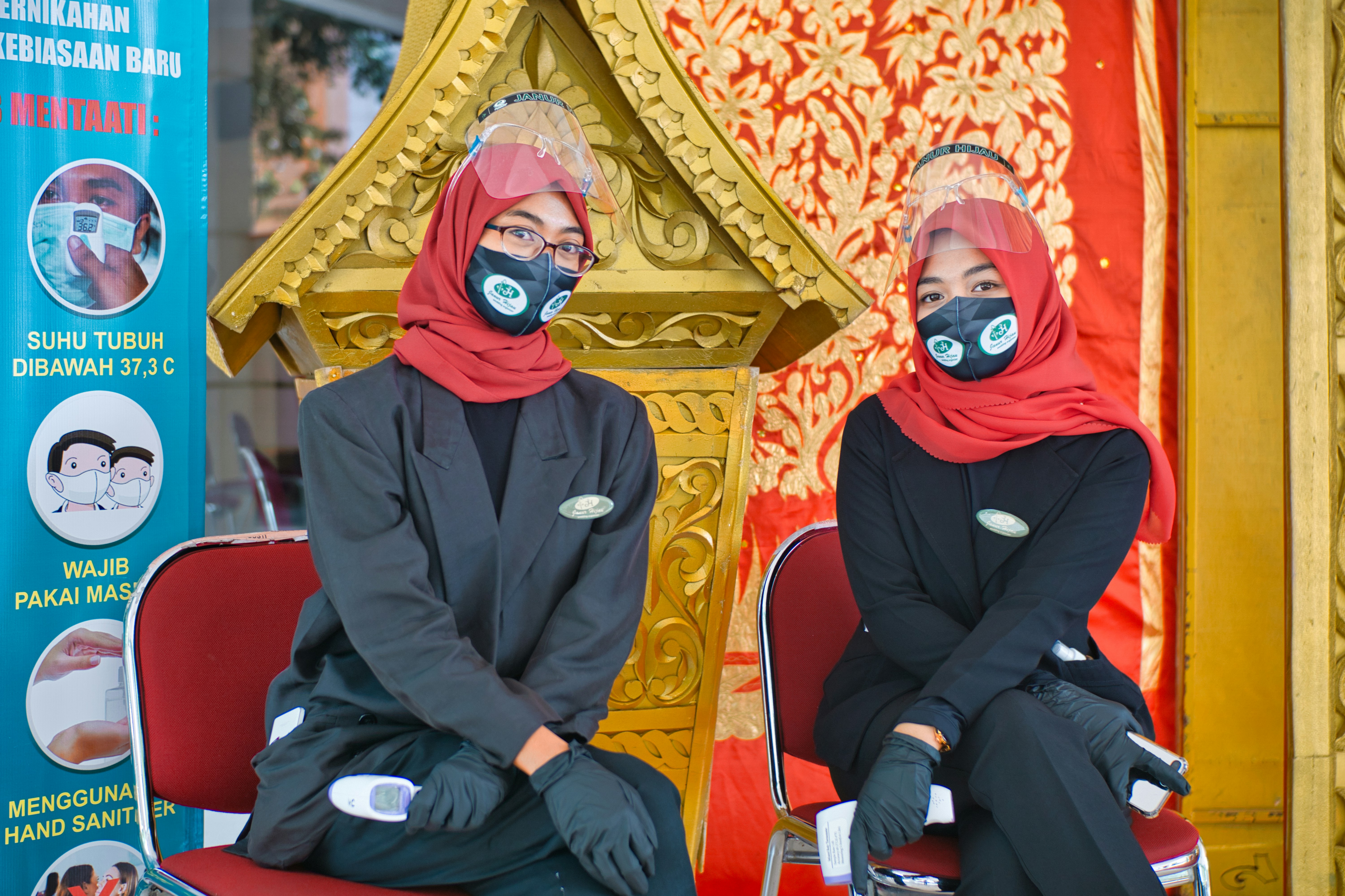 man in black jacket sitting on red and gold chair