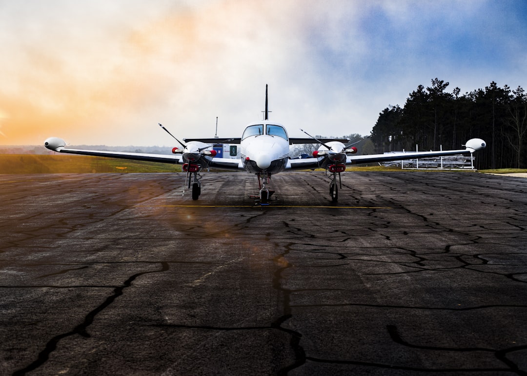 white airplane on brown field under gray clouds, Turboprop plane parked at FBO.