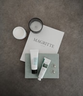 Minimal flat lay of natural beauty products and a warm taupe journal beside a pilates ring.