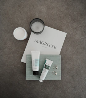 Elegant flat lay of a candle, a vinyl record, and a Gold Standard cologne bottle on a dark wood table.