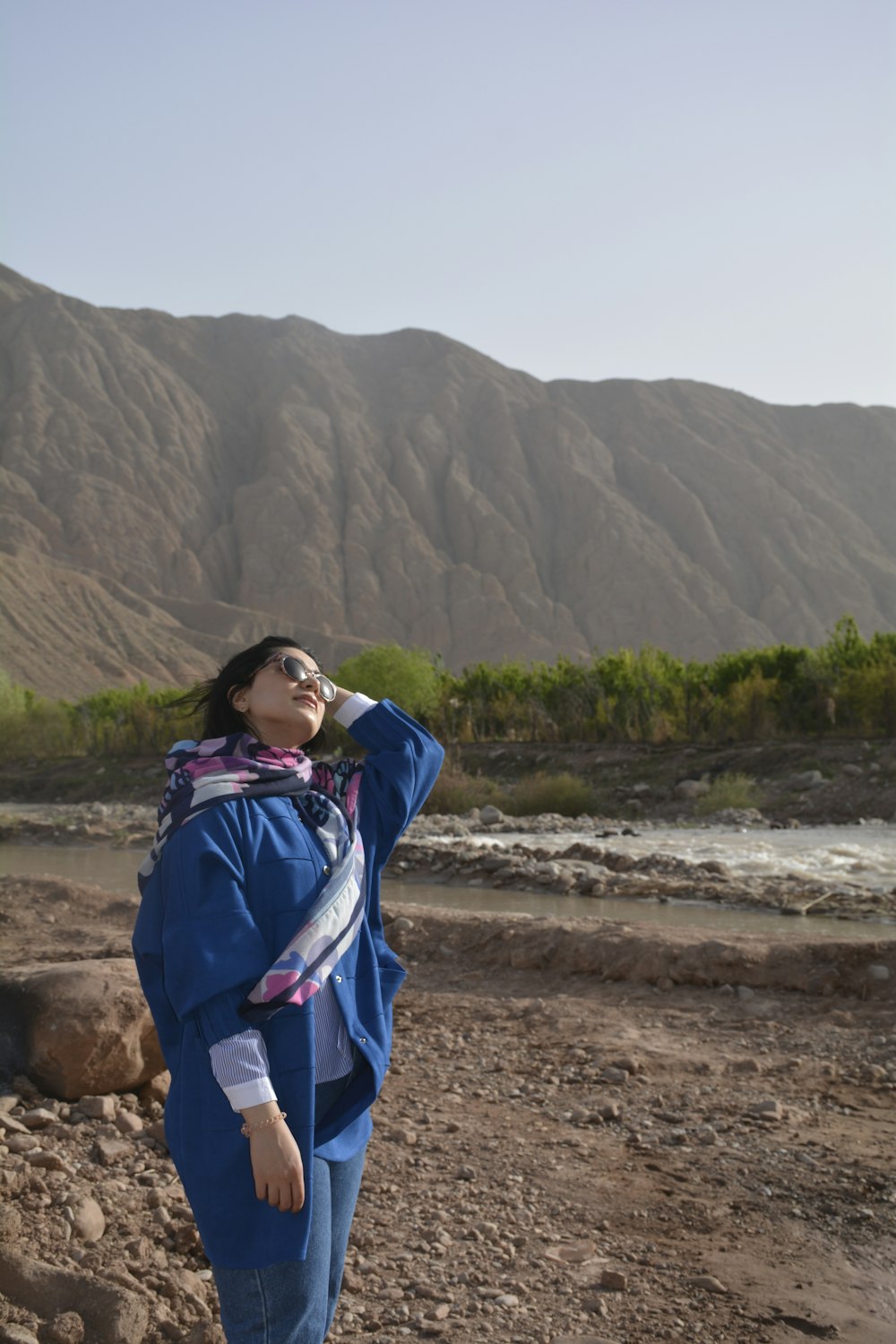 woman in blue jacket standing on brown sand during daytime