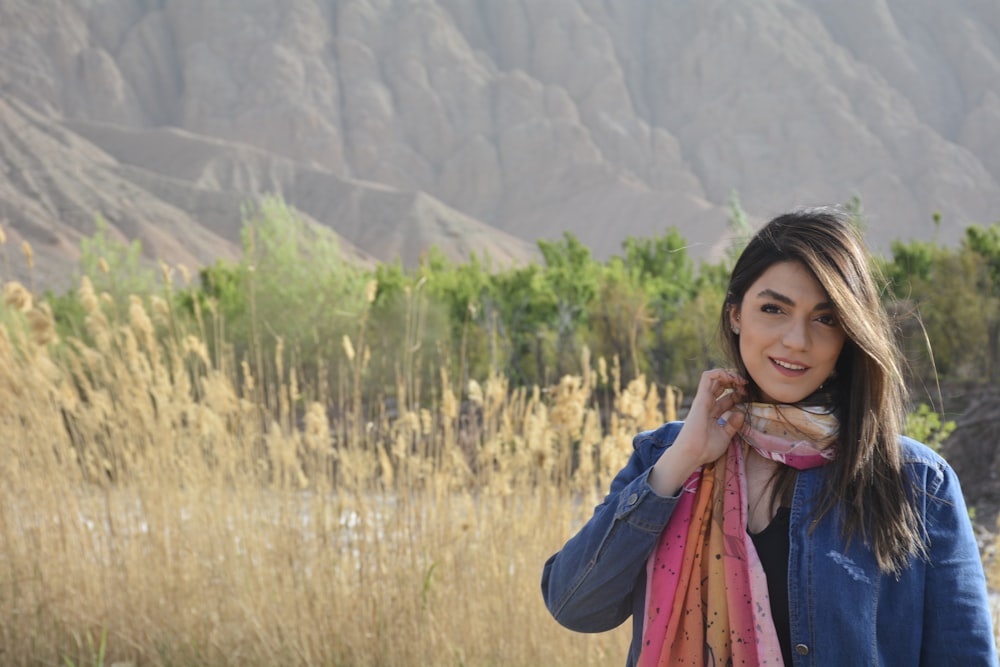 woman in blue long sleeve shirt and yellow scarf standing on green grass field during daytime