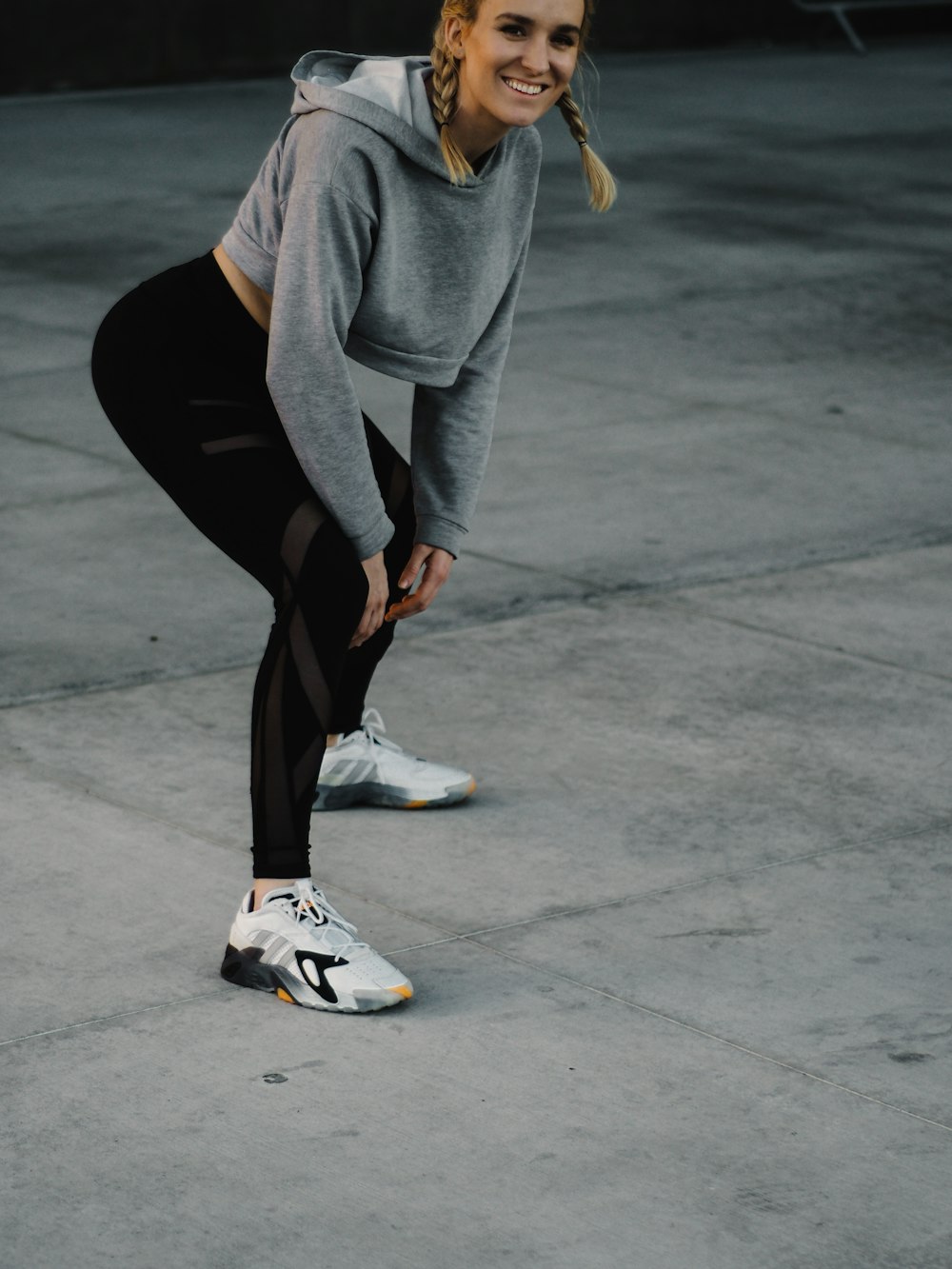 woman in gray long sleeve shirt and black leggings sitting on gray concrete floor