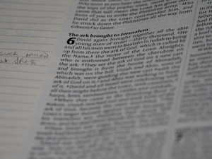 A close-up view of an open book with visible text. The page appears to be from the Bible, particularly featuring a passage with a large number '6' and a chapter title 'The ark brought to Jerusalem'. There is handwritten text in the left margin of the page.