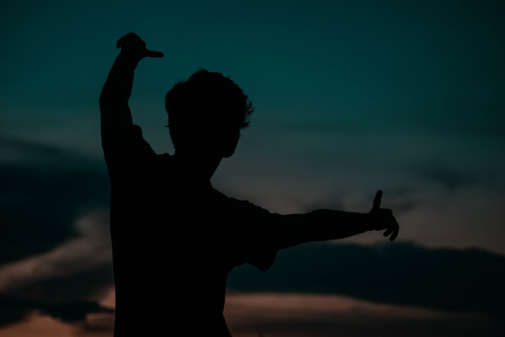 silhouette of man raising his right hand