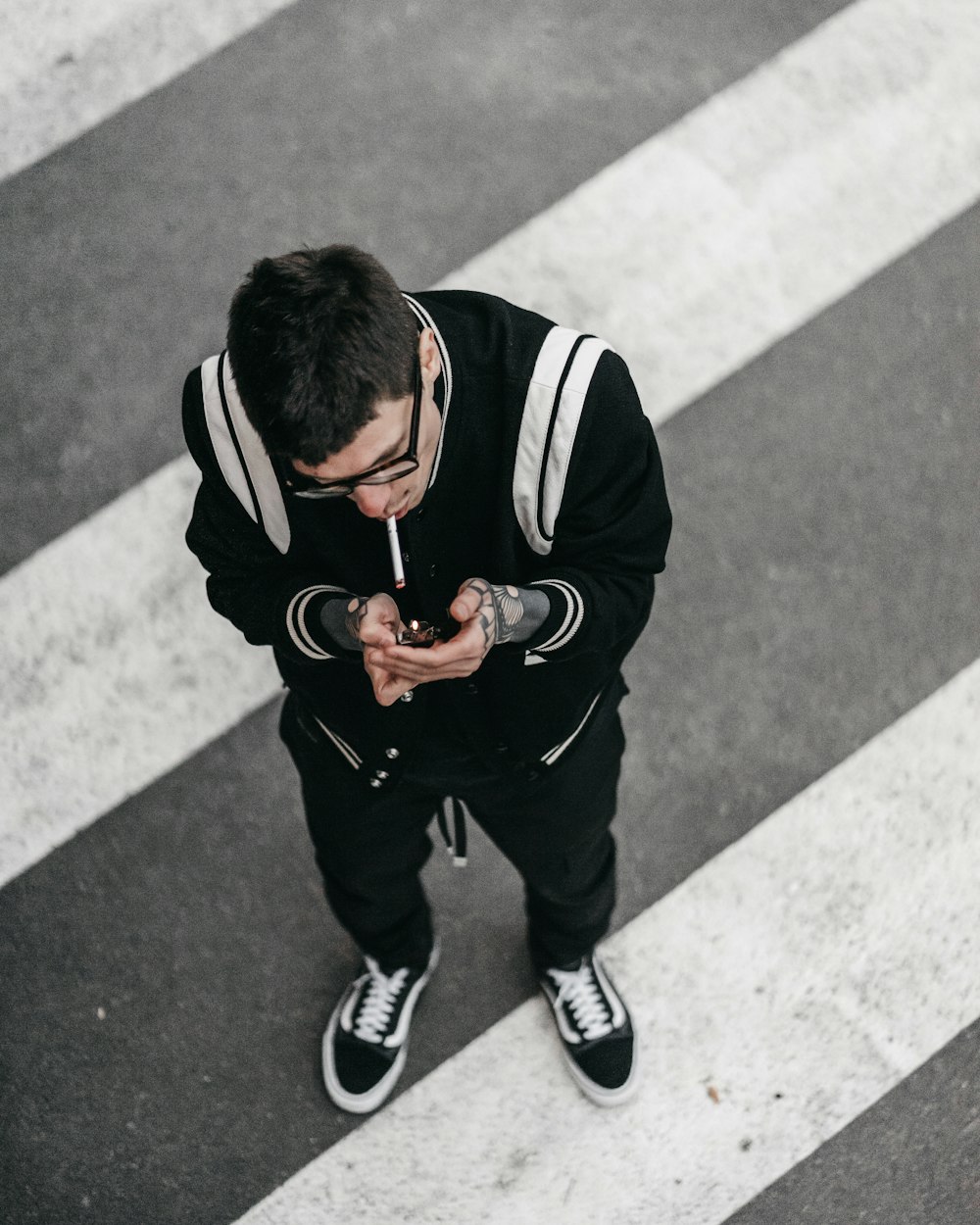 man in black and white jacket and black pants sitting on concrete floor