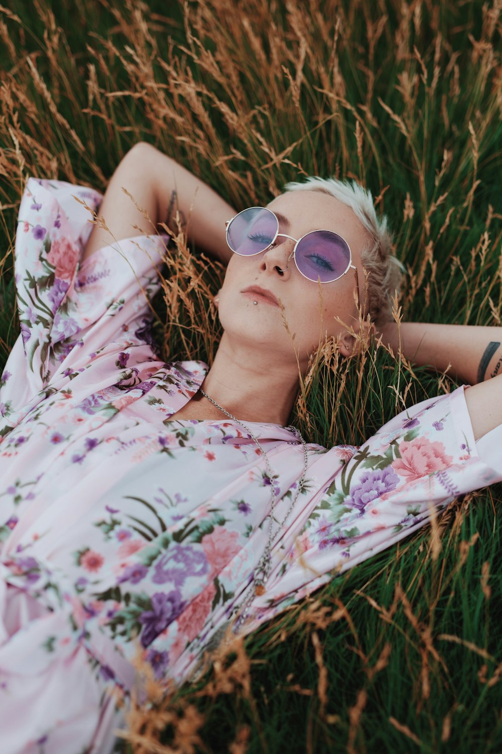 woman in white floral dress lying on grass field