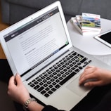 A candid moment of an author typing on a keyboard with AI news articles open on screen.