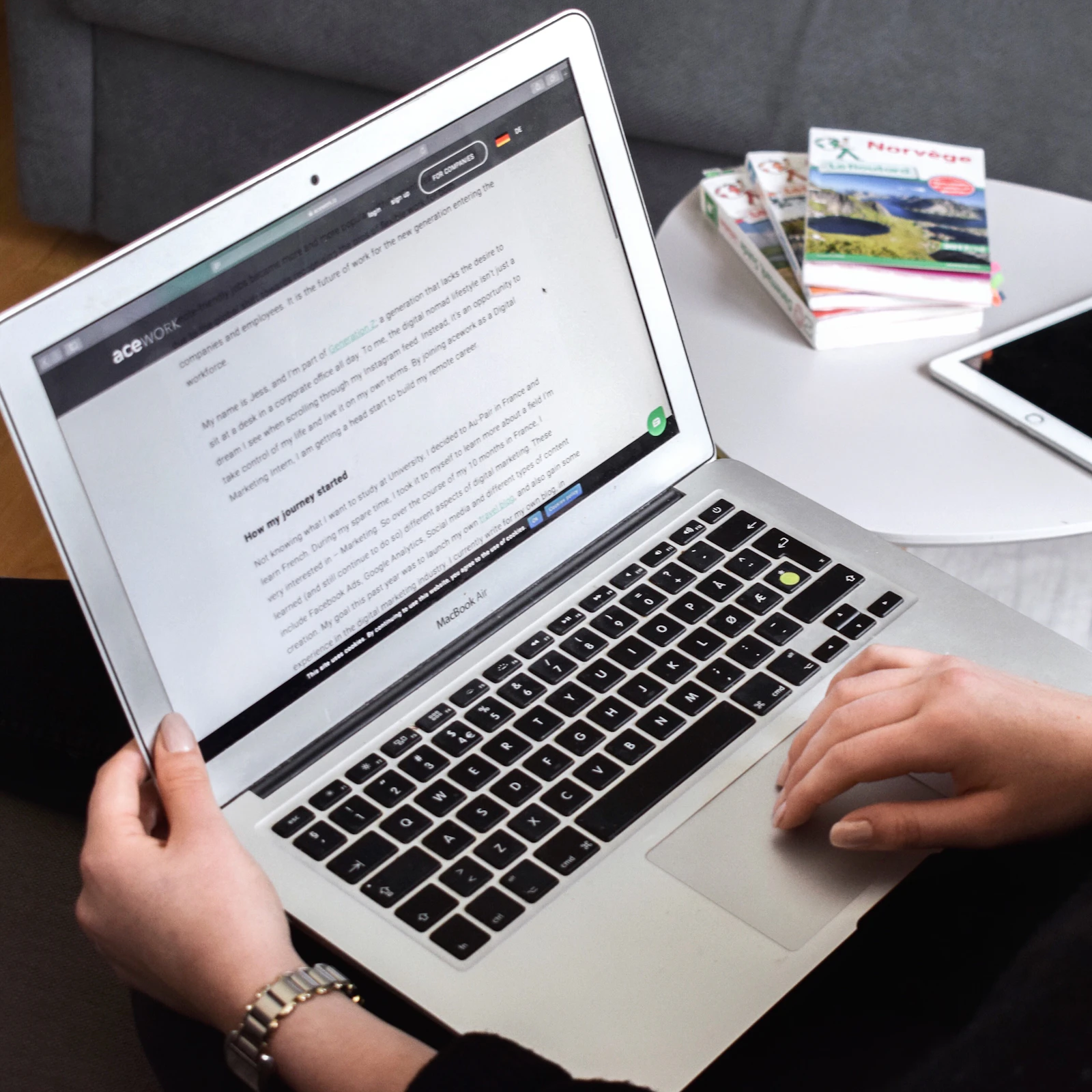 Hands reading a document on a laptop beside reference books