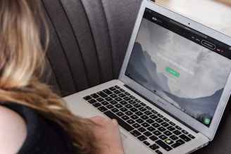 person using macbook air on gray couch