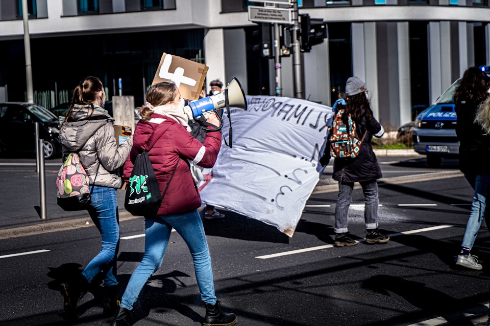 woman in red jacket and blue denim jeans holding white paper bag