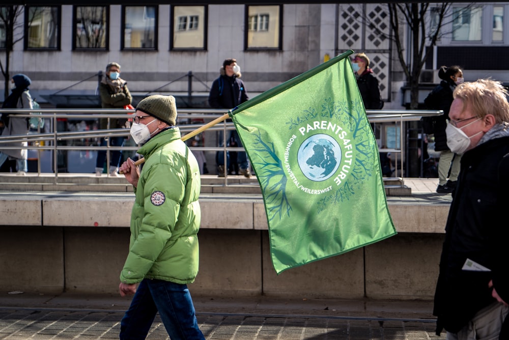 Hombre con chaqueta verde sosteniendo bandera verde