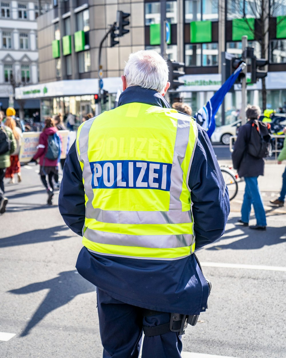 homme en veste jaune et noire marchant dans la rue pendant la journée