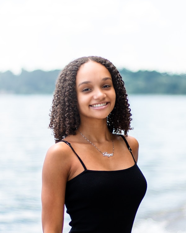 Portrait of a girl in a black top smiling at the beach. by Dillon Kydd