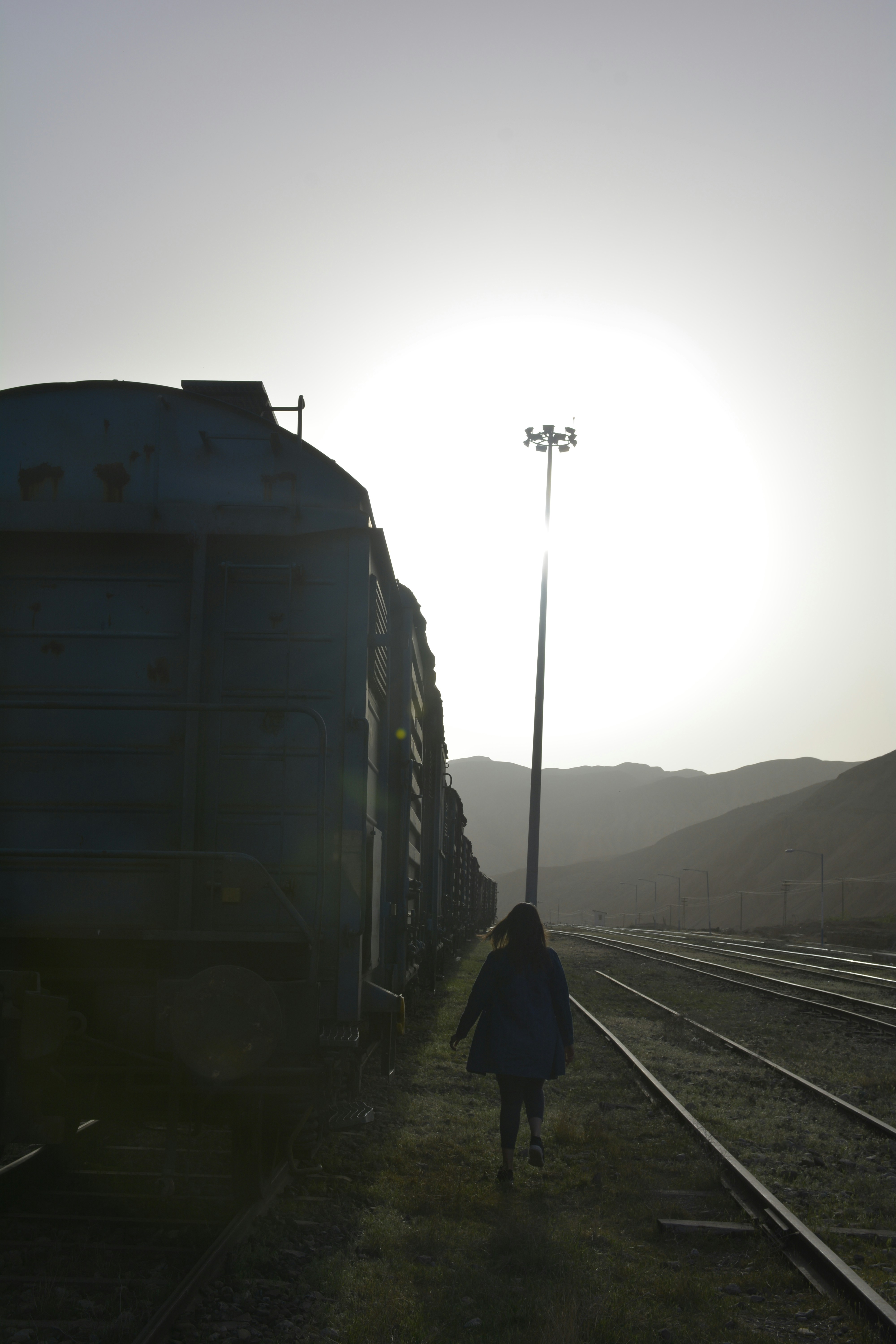 man in black jacket standing on train rail during daytime