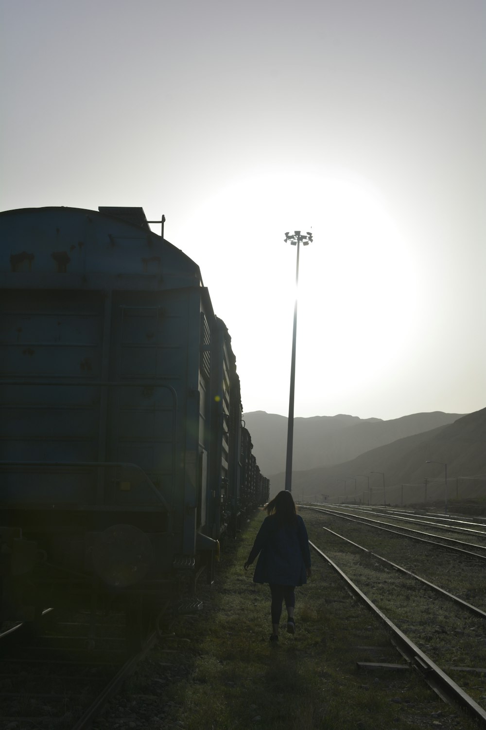 hombre con chaqueta negra de pie en el riel del tren durante el día