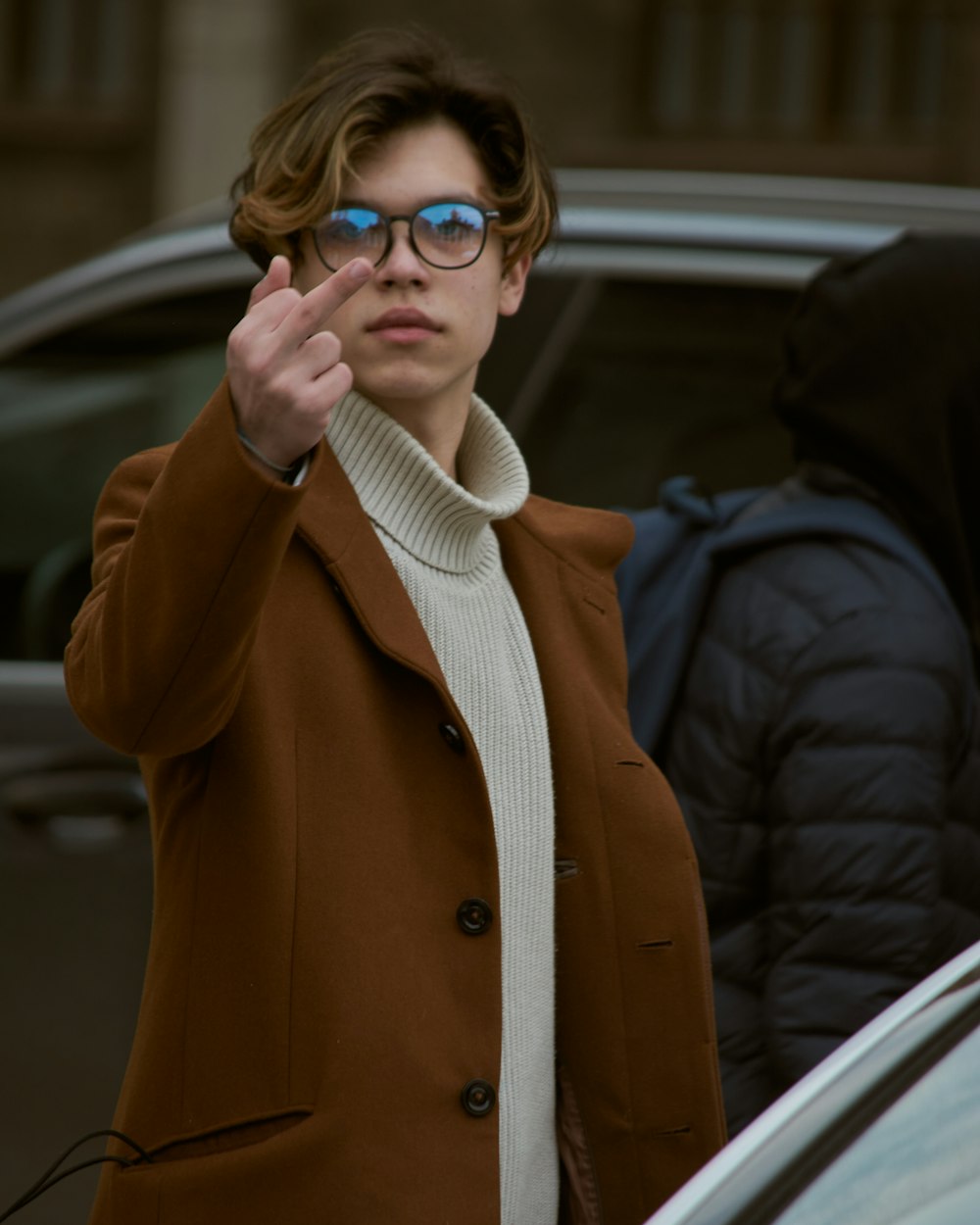 woman in brown coat wearing blue framed eyeglasses