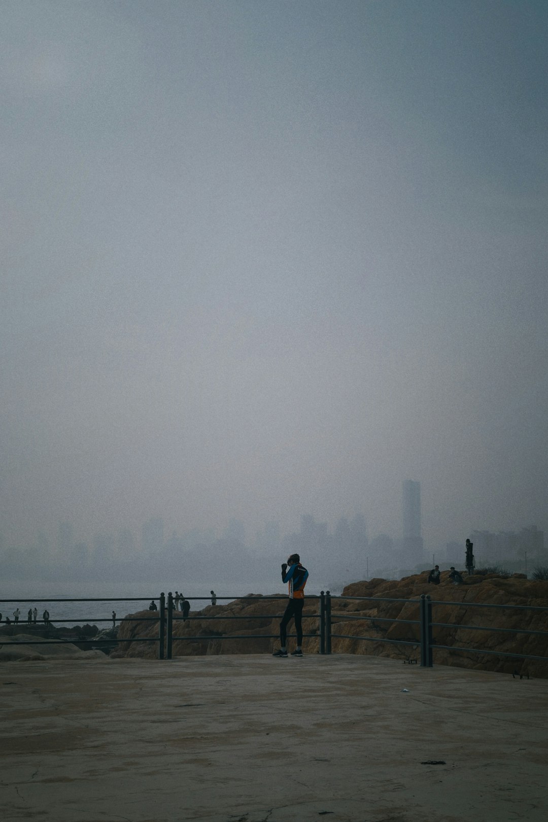 man in black jacket standing on brown wooden dock during foggy weather