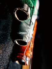 Close-up of a colorful embroidered fabric bag resting beside sewing threads and needles on a wooden table.