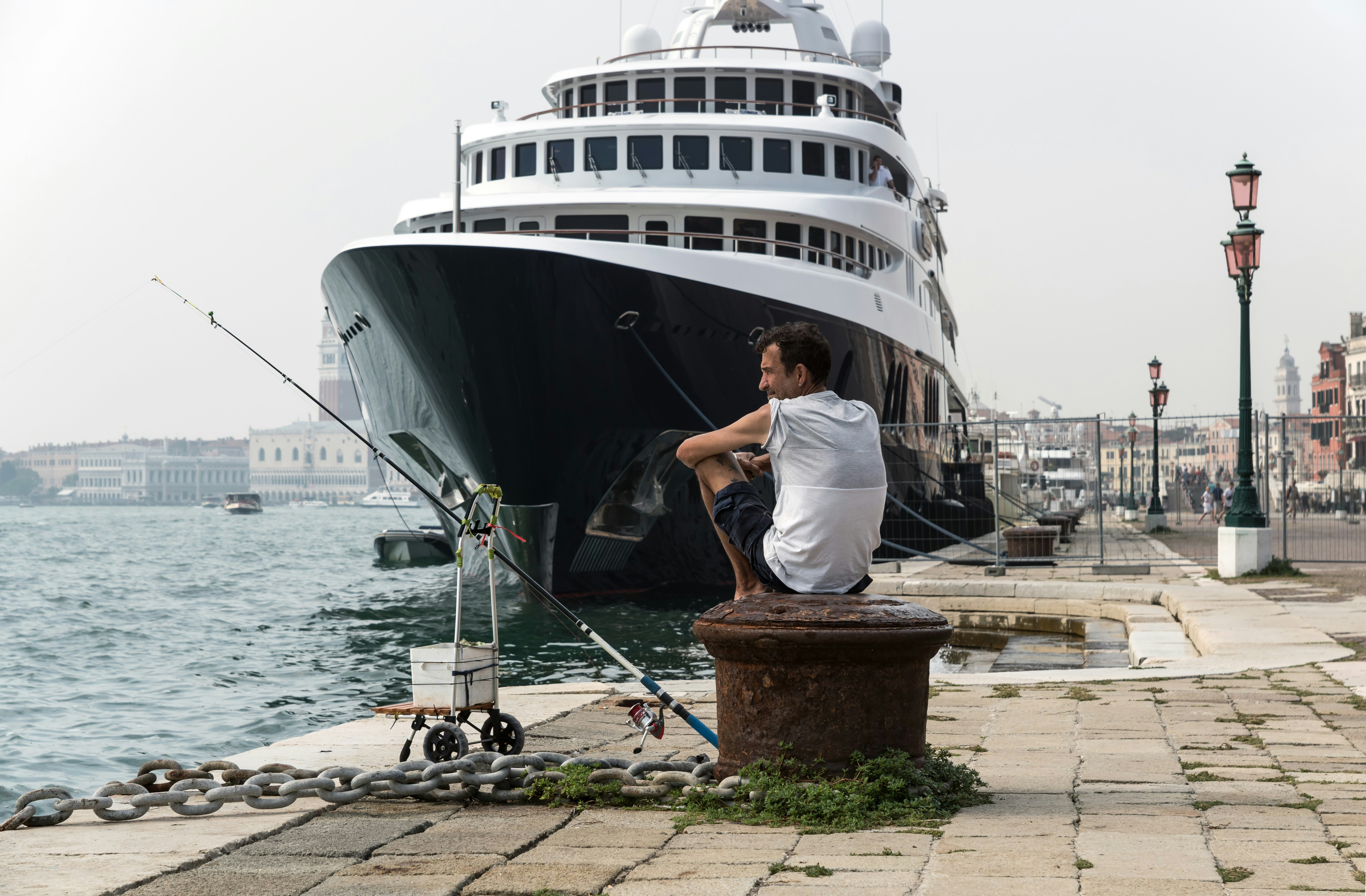 man in white shirt and blue denim jeans sitting on brown wooden box