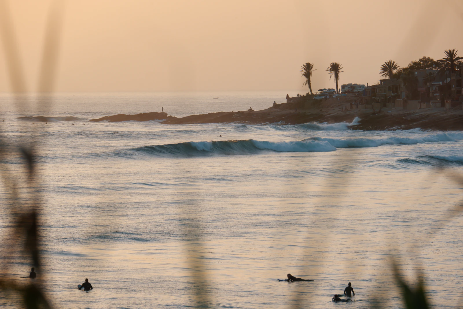 Surfers in the lineup at sunset off the rocky point at Taghazout, Morocco