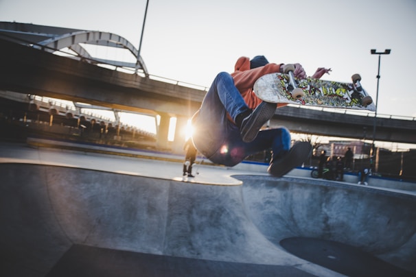 A skater performing a kickflip on a city street at sunset.