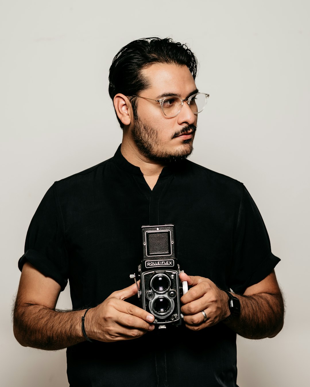 man in black crew neck t-shirt holding silver camera