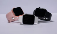 Collection of fitness trackers and smartwatches in different colors on a clean white surface.