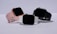 Three smartwatches are displayed on a light background. They feature different colored bands: pink, white, and black. The watches have large, rectangular touchscreens, and they are positioned to show off their sleek and modern design.