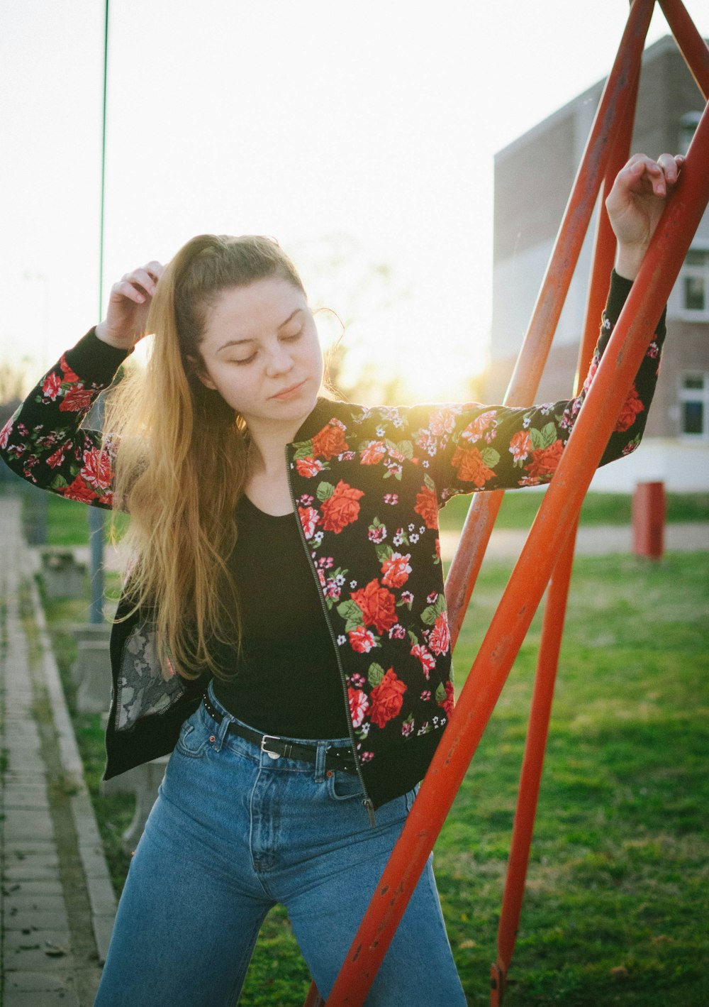 woman in black and red floral shirt and blue denim jeans standing on green grass field